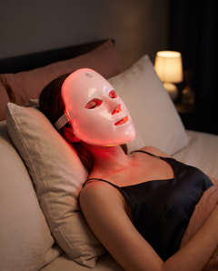 The mask worn while reclining in a dim bedroom, eyes closed, red light on